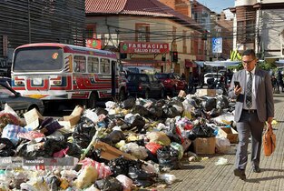 تردد ساکنان محله تامبورادا از میان زباله‌ها انباشته شده (بدلیل اختلاف بر سر زمین دفن زباله) در کوچابامبا، بولیوی