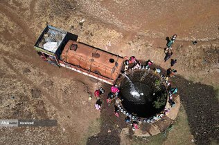 نمایی از تانکری در نزدیکی بمبئی هند که آب را به داخل چاهی تخلیه می‌کند و زنان از آن آب می‌کشند.