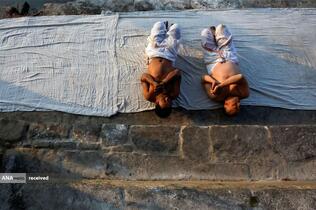 مراسم دعا و غلتیدن بر روی زمین در فستیوال یک ماهه سواستانی براتا کاتا در ساحل رودخانه هانومانته در باکتاپور، نپال