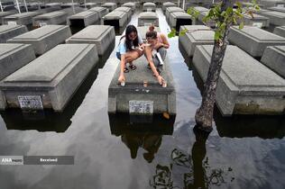 برافروختن شمع بر روی قبور نیمه غوطه ور در پارک یادبود روح القدس در ماسانتول استان پامپانگا، فیلیپین