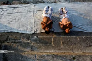 مراسم دعا و غلتیدن بر روی زمین در فستیوال یک ماهه سواستانی براتا کاتا در ساحل رودخانه هانومانته در باکتاپور، نپال