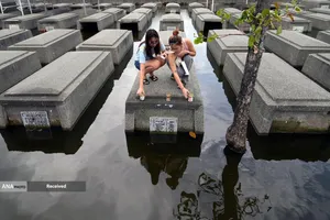 برافروختن شمع بر روی قبور نیمه غوطه ور در پارک یادبود روح القدس در ماسانتول استان پامپانگا، فیلیپین