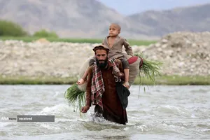 عبور کشاورز افغان با پسرش از رودخانه ای در شهر محترلم استان لغمان، افغانستان