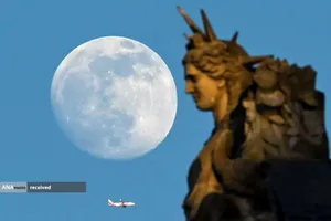 تصویر ماه کامل و پرواز هواپیما در آسمان پاریس